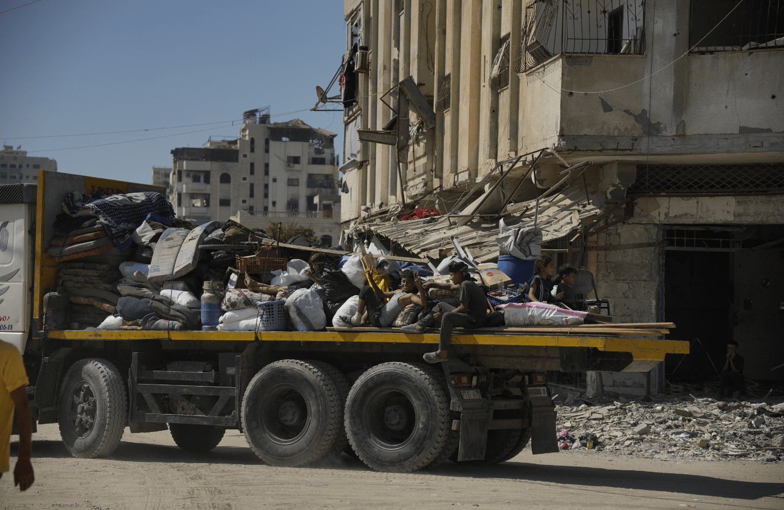 A flatbed truck carrying families and their belongings through a war-torn street in Gaza