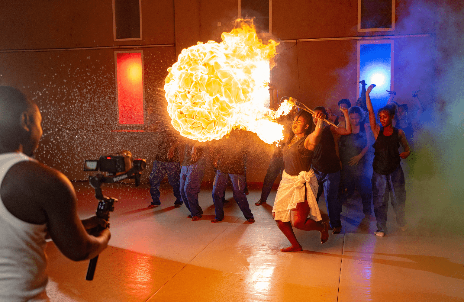 A fire breather performs while other dancers are in the background