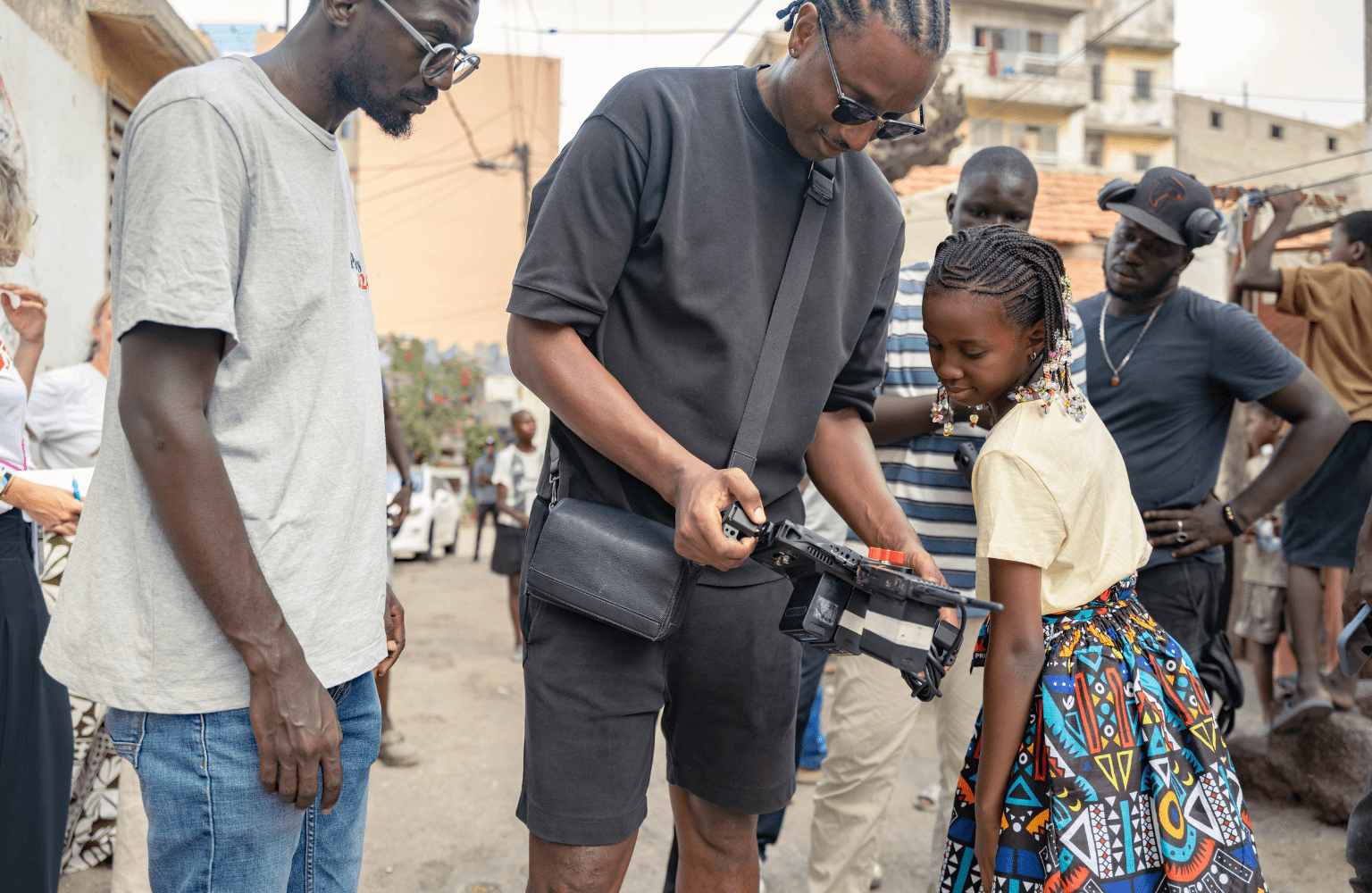 Audy Valera (center) shows a video to Racky Imanyé Sowl on the set of the Clima Yaakaar music video in Reubeuss, Dakar